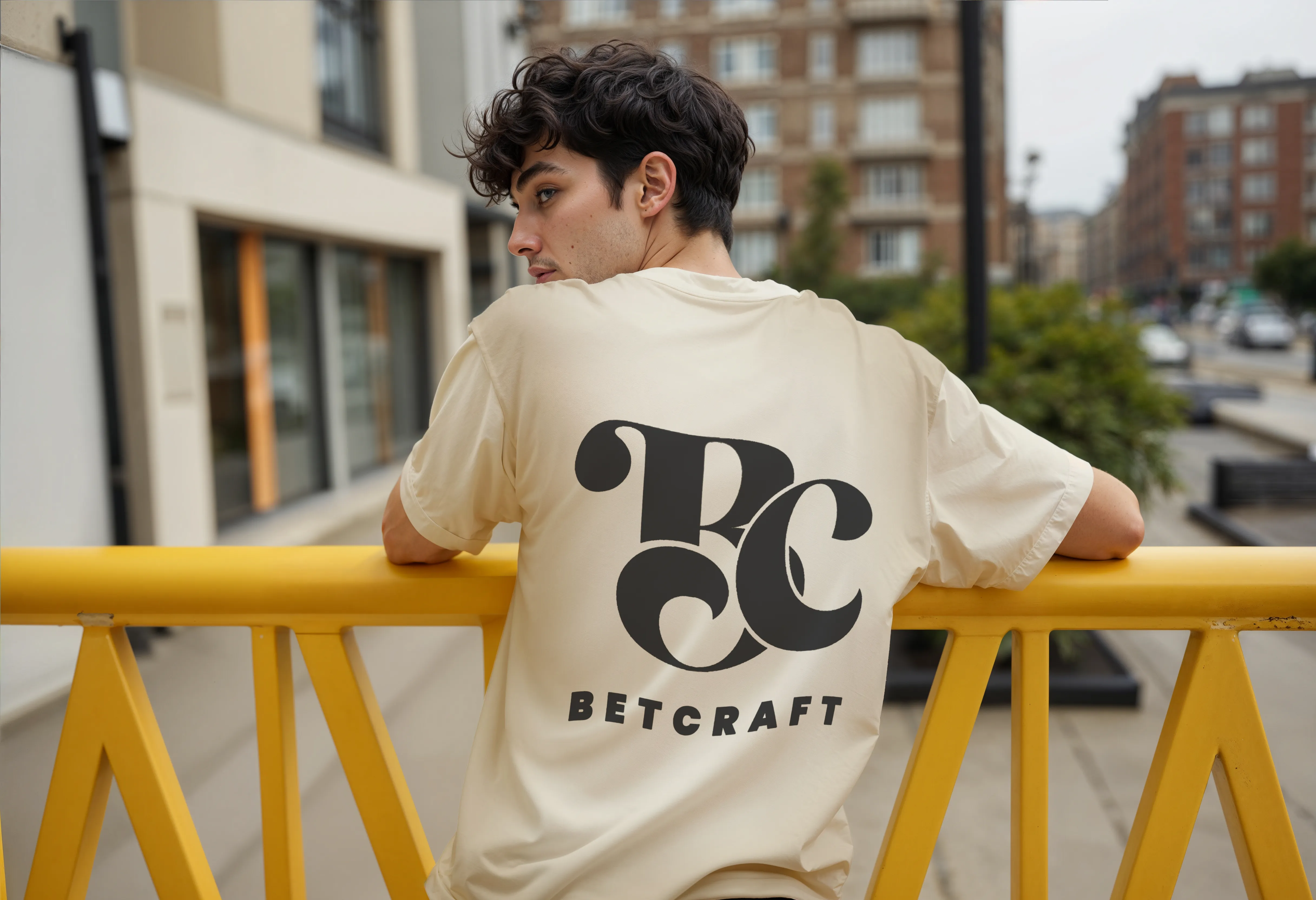 Chico de espaldas con camisa beige estampada con logo de Betcraft.